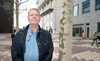 En man som står bredvid en trädstam.