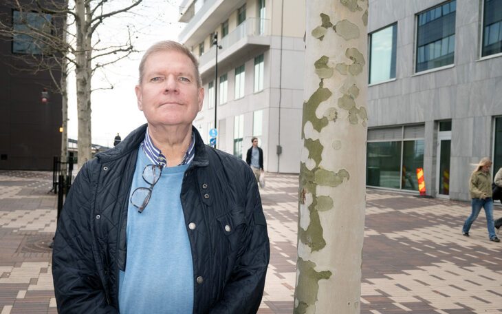 En man som står bredvid en trädstam.