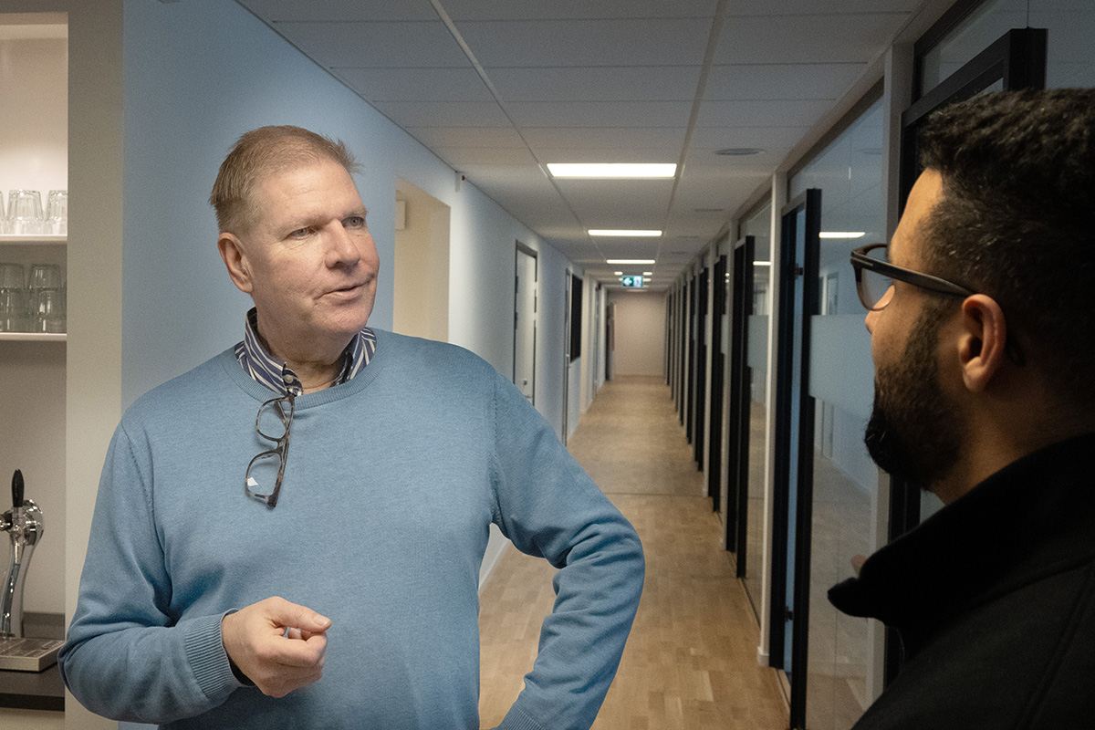En man som pratar med en annan man som har ryggen mot betraktaren.