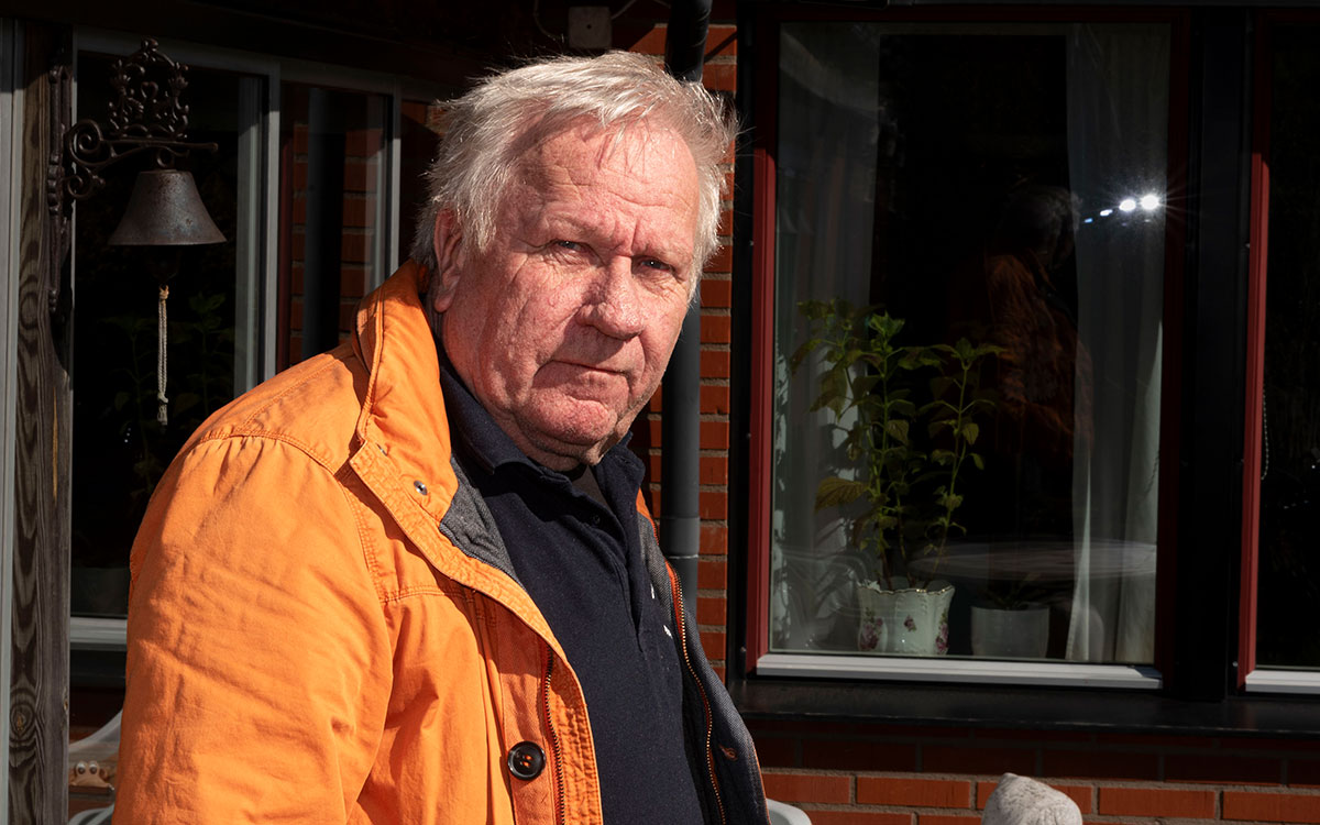 En äldre man i en orange jacka.