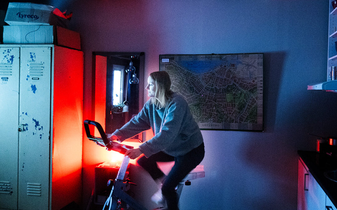 En kvinna som sitter på en trampcykel i ett mörkt rum.
