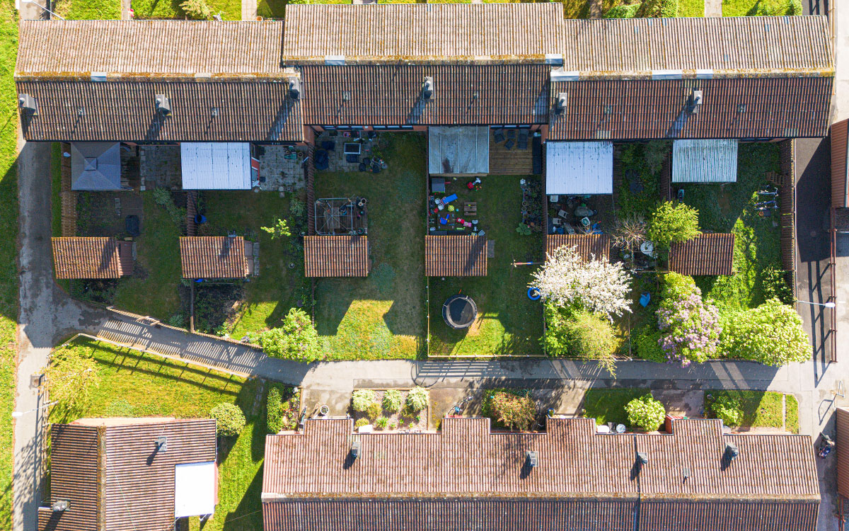 En bild tagen ovanifrån som visar uterum på baksidan av flerbostadshus i en grön, vårig miljö.
