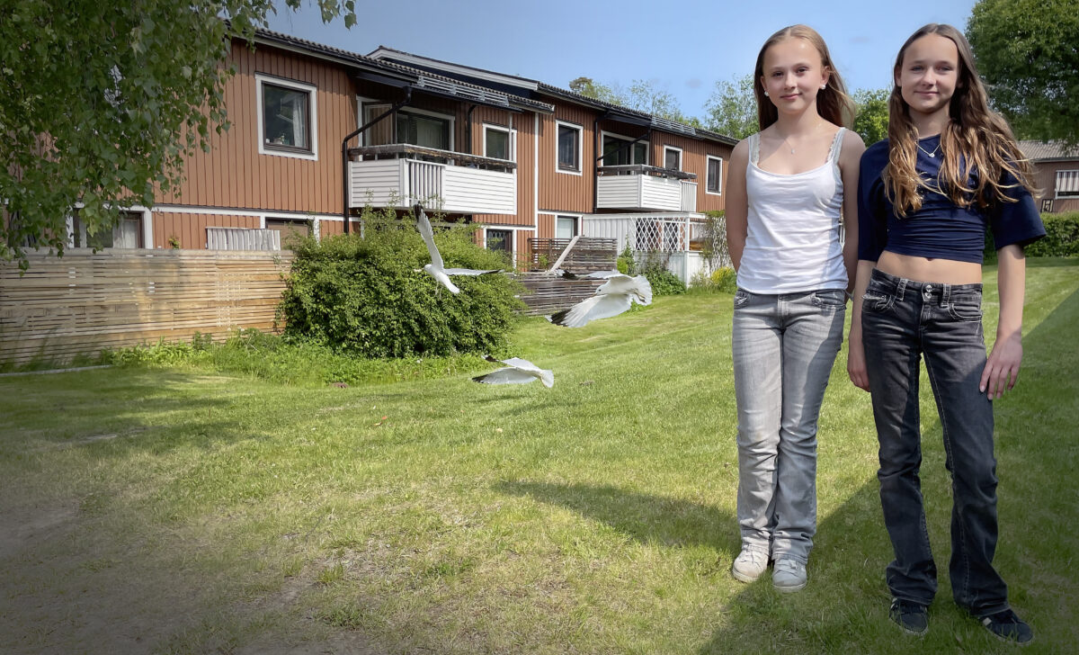 Två flickor i 12-årsåldern framför ett bostadsområde med tvåvåningshus.