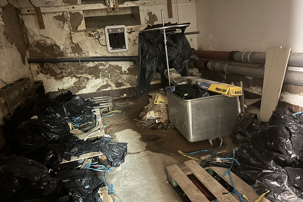 En källarrum som är fullt av bråte, bland annat svarta plastpåsar.