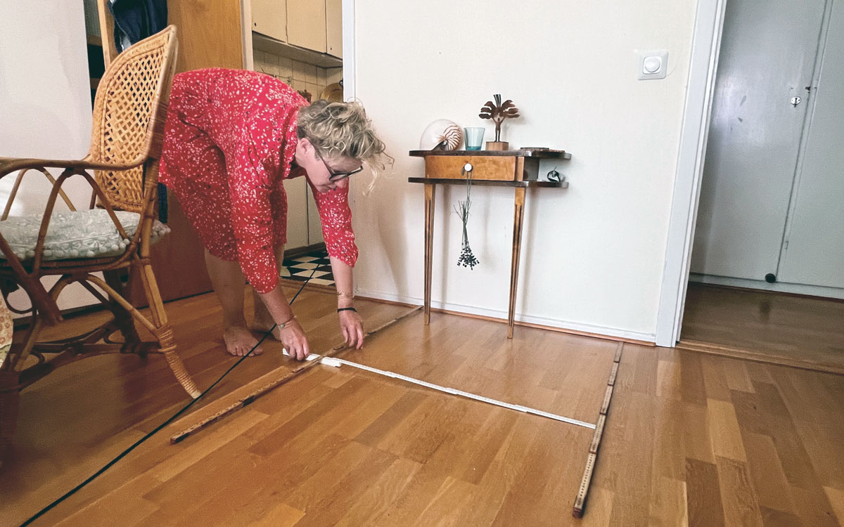 Karin Persson mäter upp duschkuben i vardagsrummet.