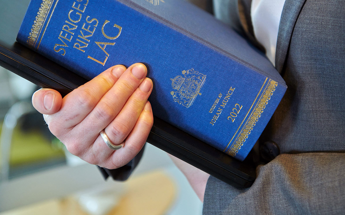 Hand som håller i en lagbok.