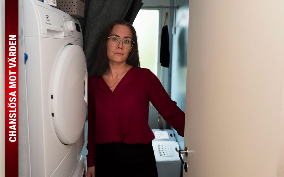 Ett foto på en kvinna i röd överdel och glasögon som står vid en torktumlare i ett badrum bakom en dörröppning, och på bilden finns texten "Chanslösa mot värden".