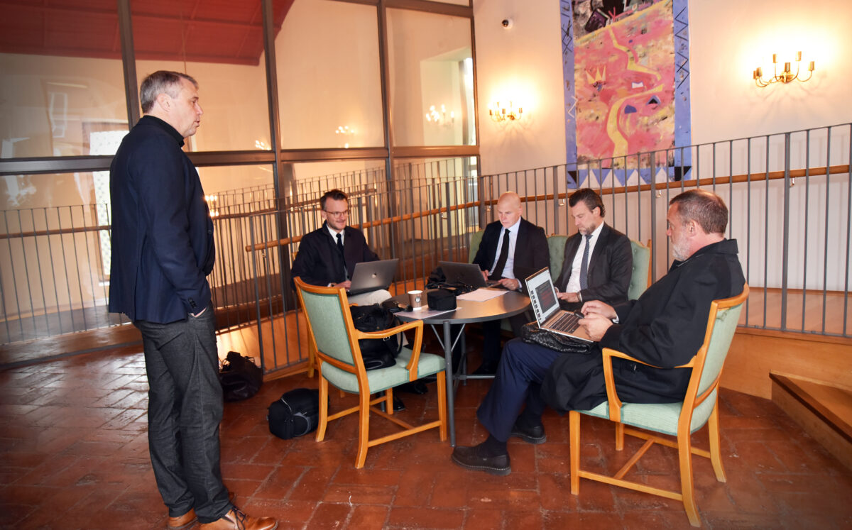 Flera kostymklädda herrar med datorer.