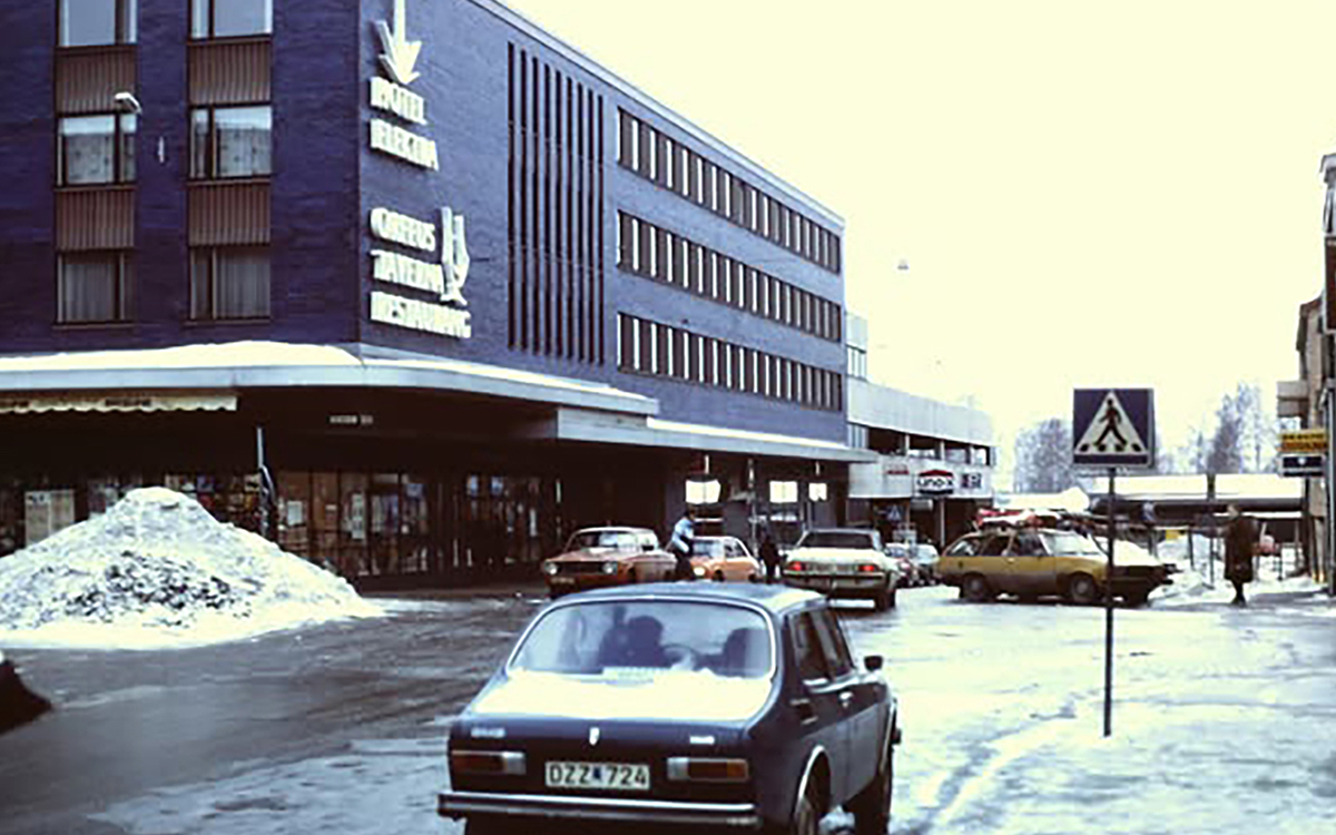 En vintrig bild från tidigt 80-tal på en gata där en Saab 99 syns i förgrunden. Här syns också en stor byggnad där det bland annat finns en skylt med orden Hotell Elektra.