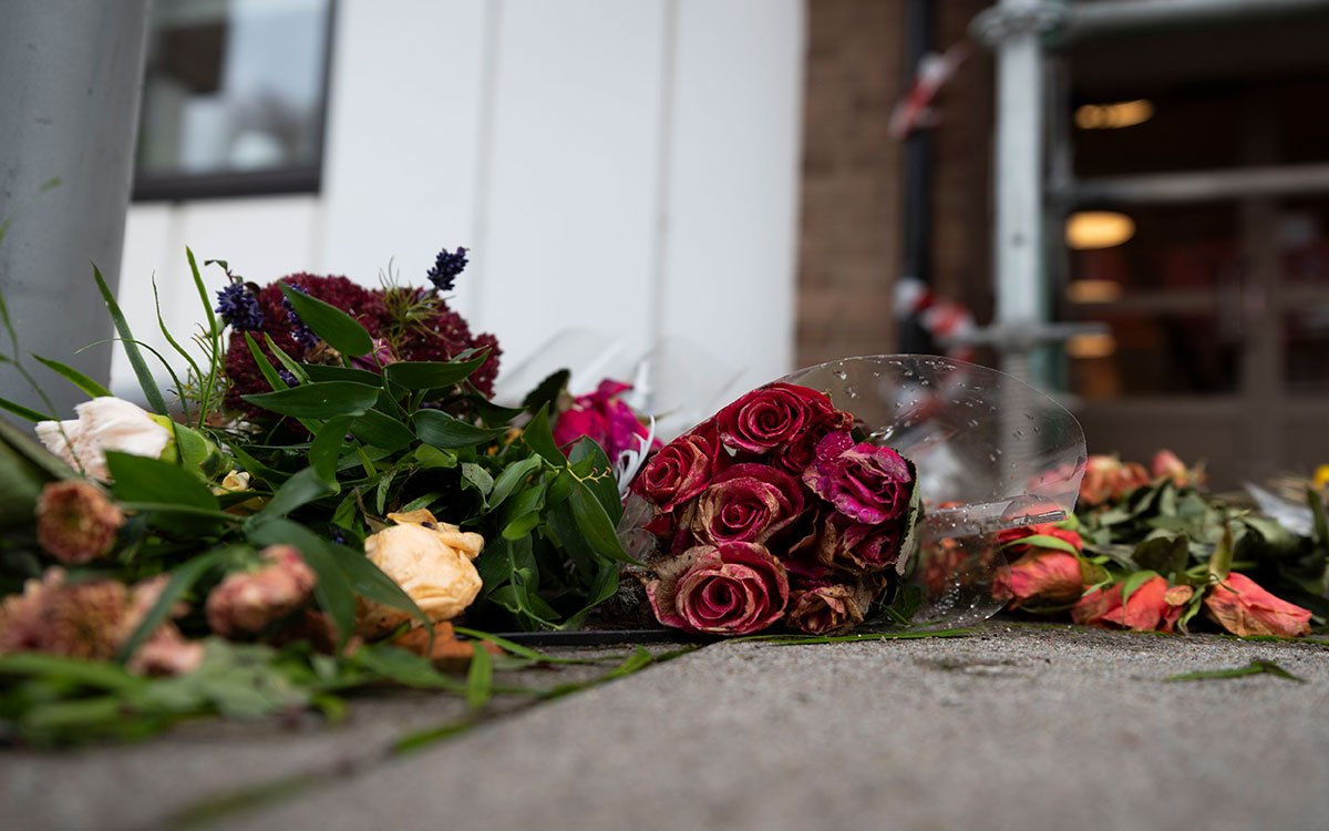 Blommor som ligger på marken utanför ett hyreshus.