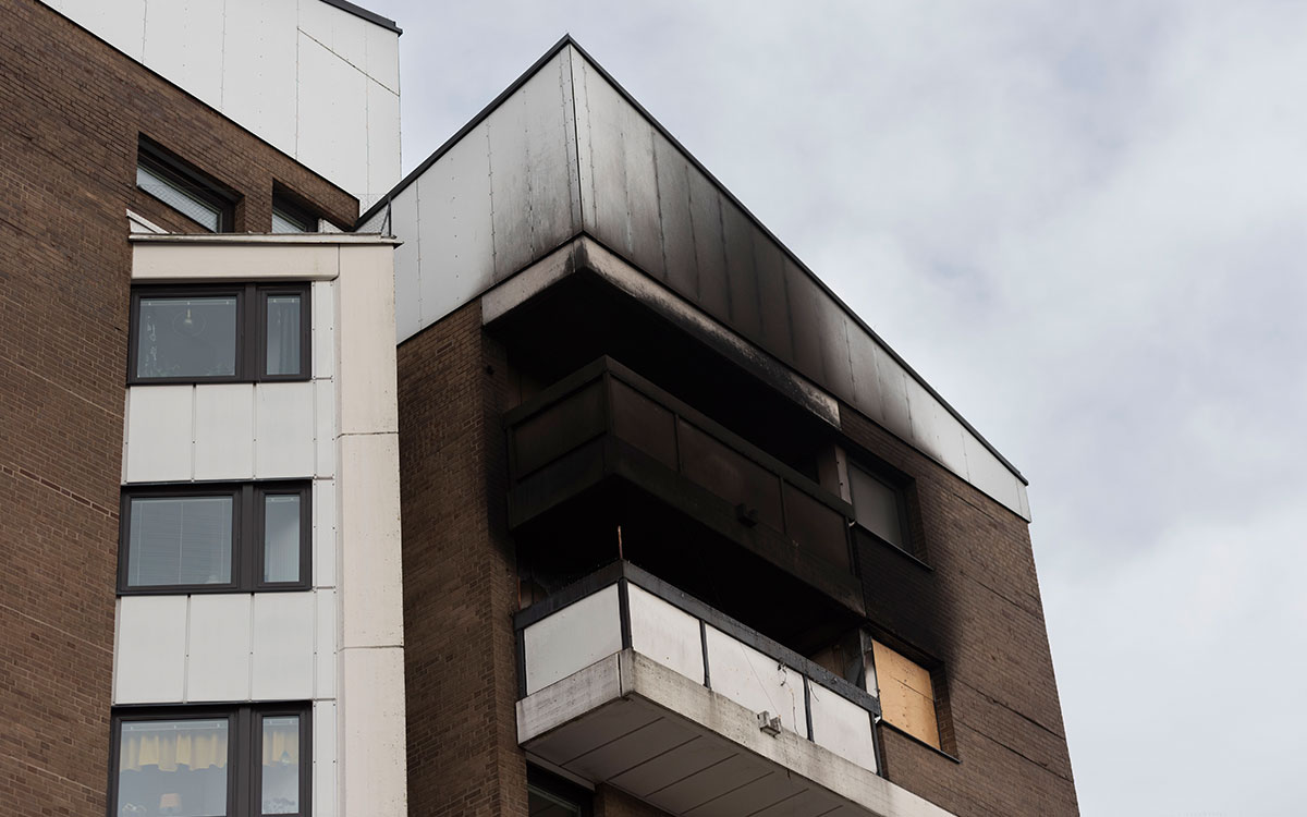 Ett flervåningshus med tydliga brandskador på den svedda fasaden.