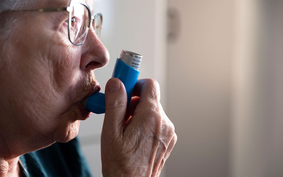 En äldre kvinna som tar läkemedel med hjälp av en inhalator.