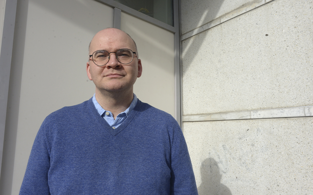 Martin Bommelin står vid en vägg utomhus.