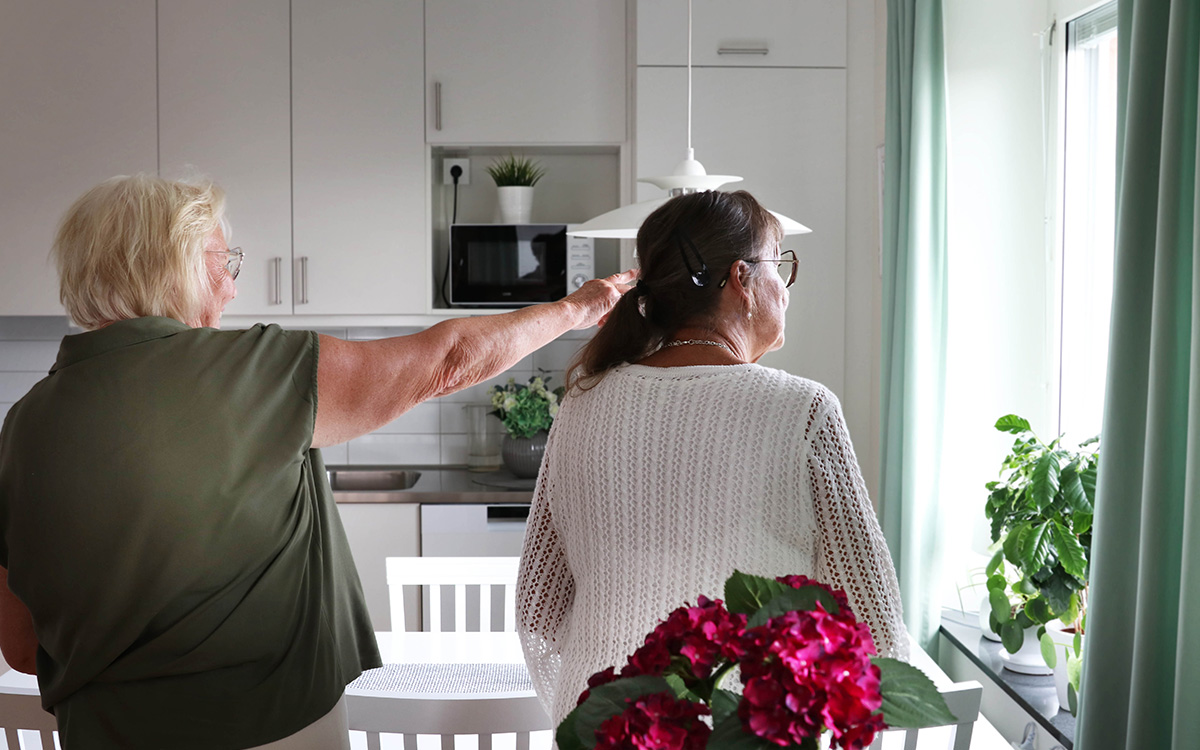 Två kvinnor som tittar ut genom ett fönster.