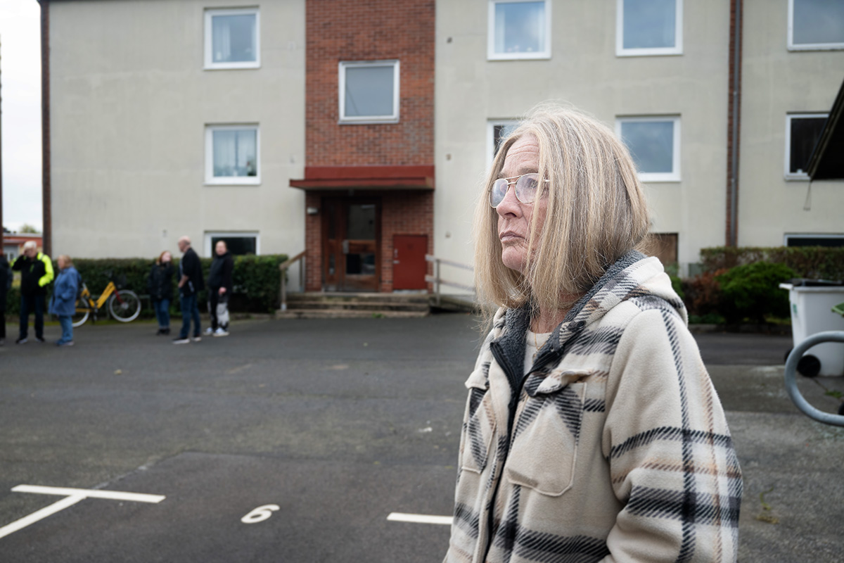 En kvinna framför ett flerfamiljshus.
