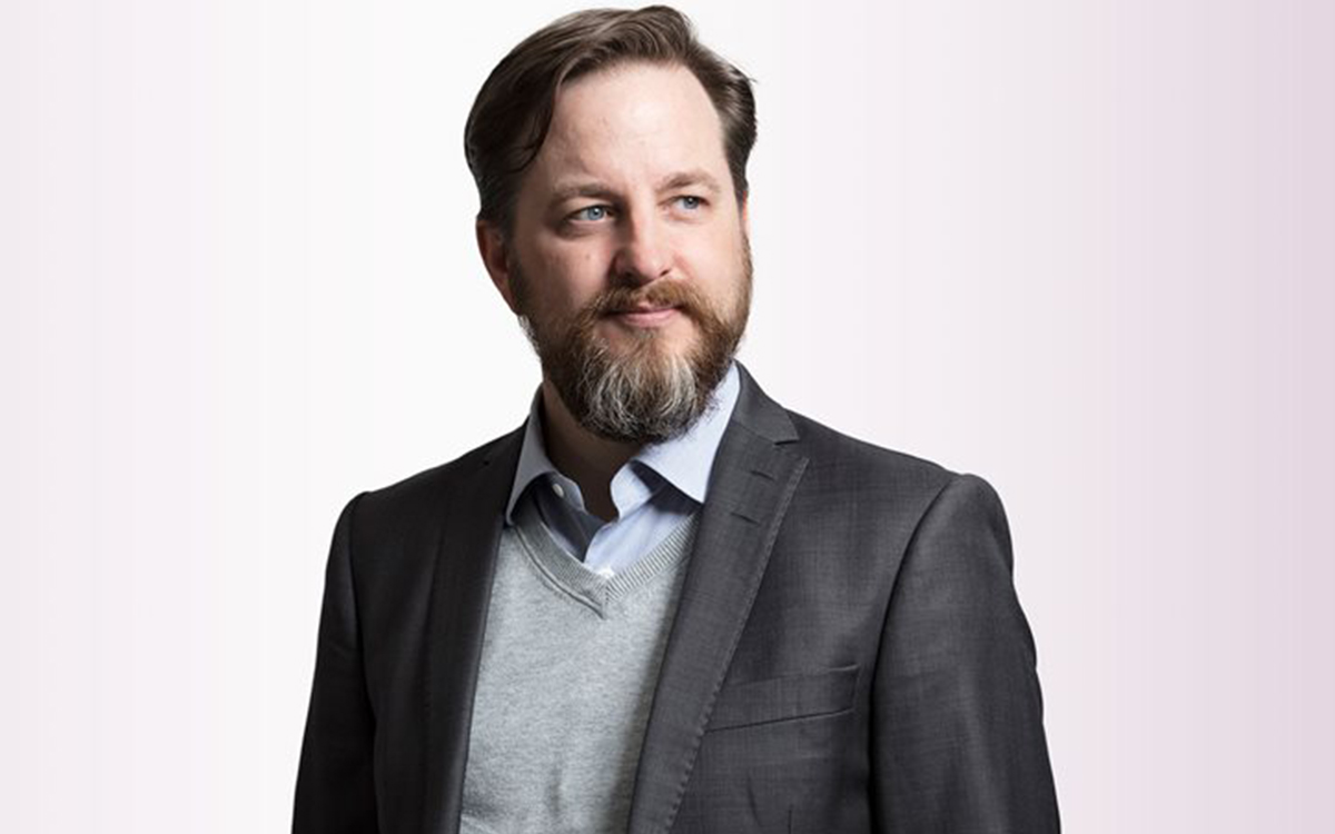 Man med skägg och kavaj som något leende tittar lite åt sidan.