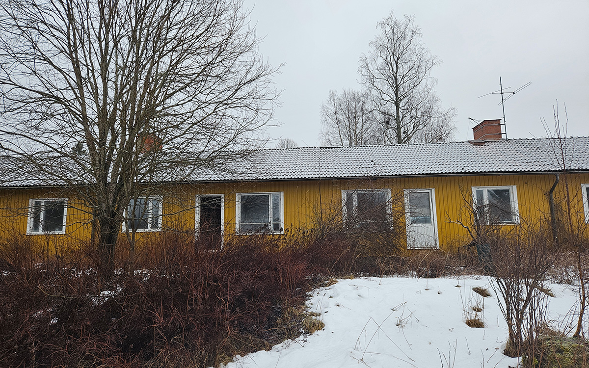 Gult, skabbigt enplanshus. Snö på marken.