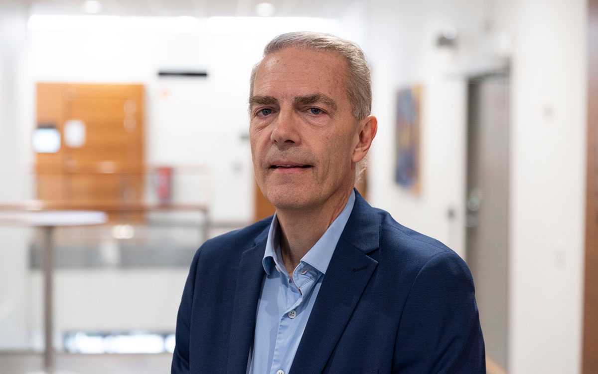 Porträtt av en man i blå kavaj, blå skjorta och grått hår.