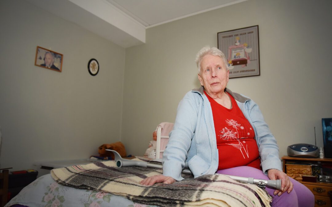 En äldre kvinna sittandes på en säng.