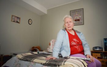 En äldre kvinna sittandes på en säng.