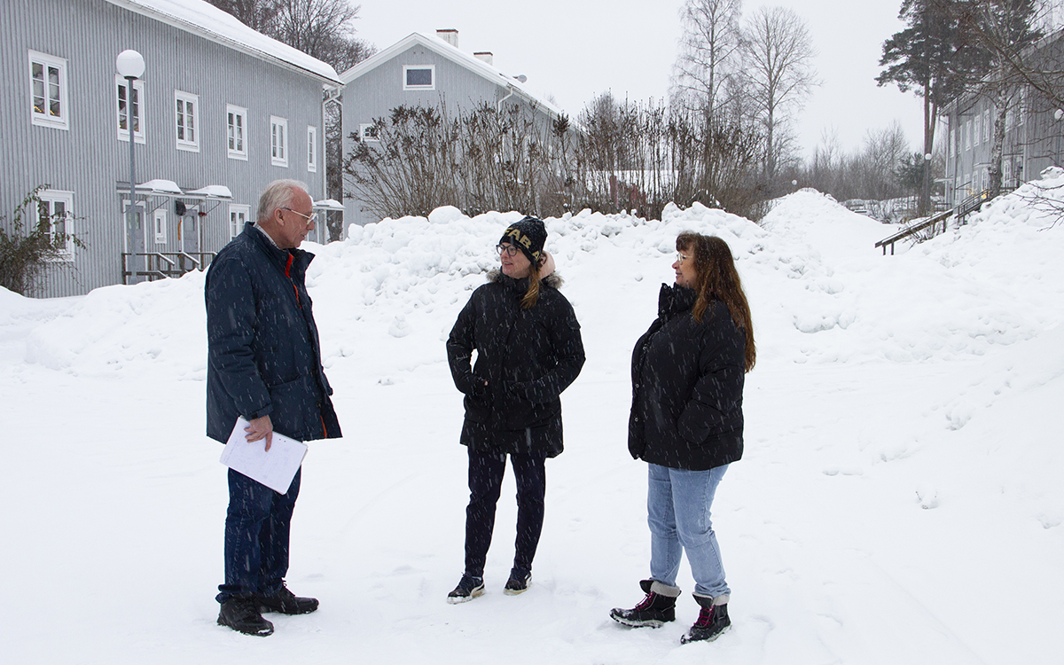 En man och två kvinnor står och pratar i snön i ett bostadsområde med tvåvåningshus i gråmålat trä. Snön faller. Hyresgästerna i Marmaverken berättade i januari 2024 om problemen med hyresvärden AB-hem. Nu har AB-hems ekonomiska problem blivit så allvarliga att det finns risk att husen tvångssäljs.
