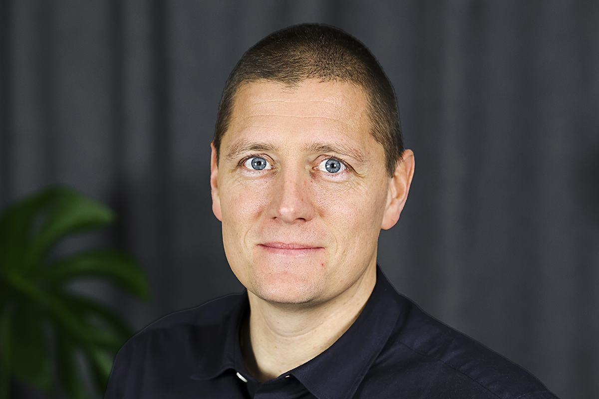 En man i svart skjorta som tittar rakt fram.