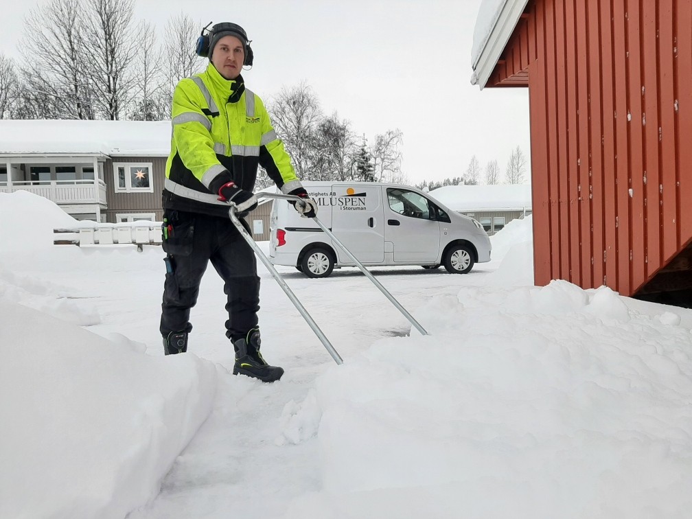 En snöskottande man i varselkläder.