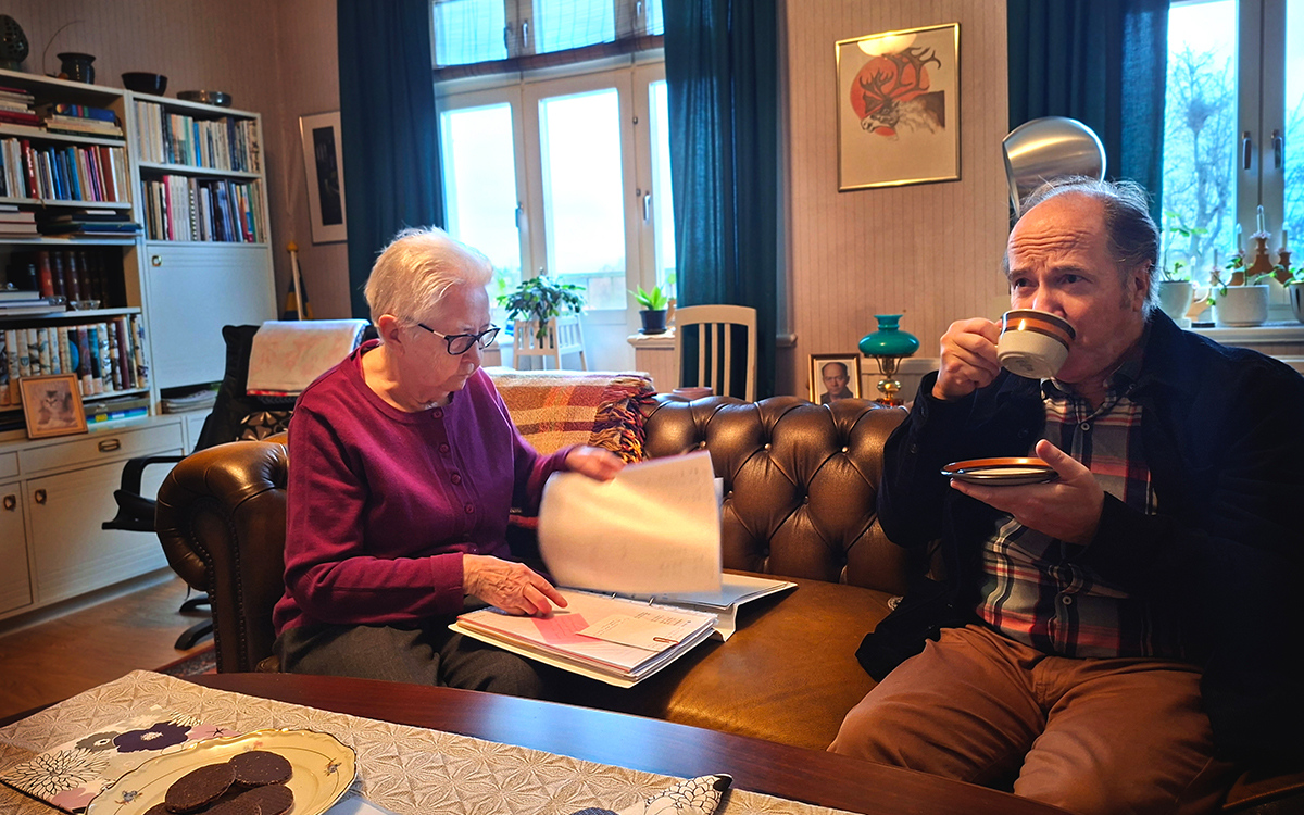 Bilden visar en man och en kvinna som sitter i en soffa. Kvinnan tittar i en pärm medan mannen dricker ur en kaffekopp.