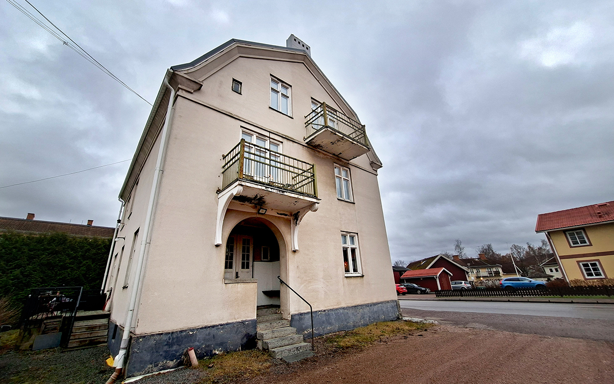 Bilden visar gaveln på ett beige stenhus. Här syns två balkonger där puts har rasat bort från undersidan av golven.
