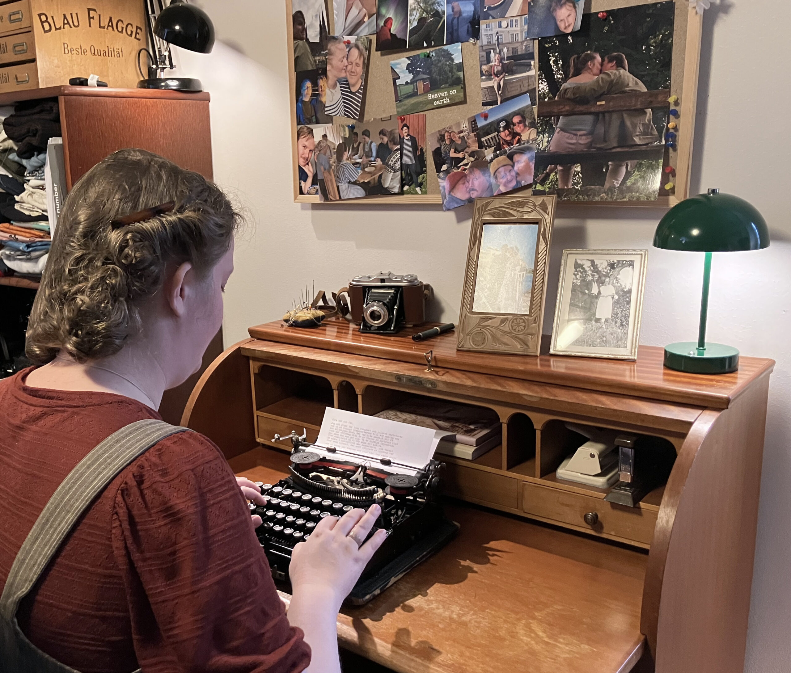 Kvinna med håruppsättning sitter vid en sekretär och skriver på en skrivmaskin.