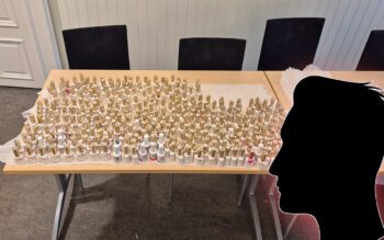 Bilden visar ett bord som är fullt med nagellacksflaskor. Inklippt i bilden syns silhuetten av en mans huvud. Silhuetten är helt i svart.