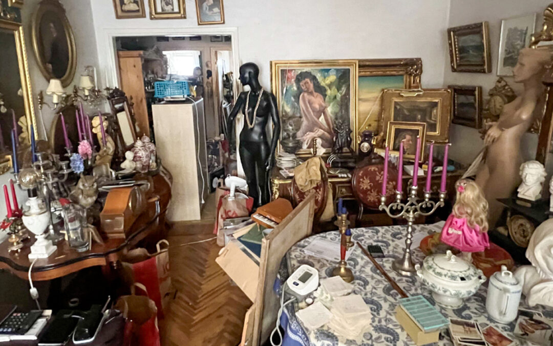 Bilden visar ett mycket stökigt rum där man bland annat ser ljusstakar, tavlor och två skyltdockor.