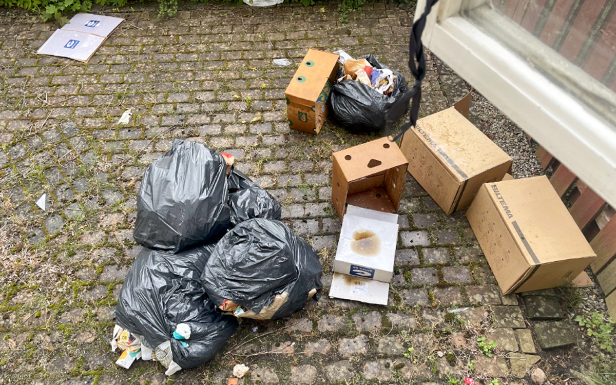 Sopsäckar och papperskartonger på marken.