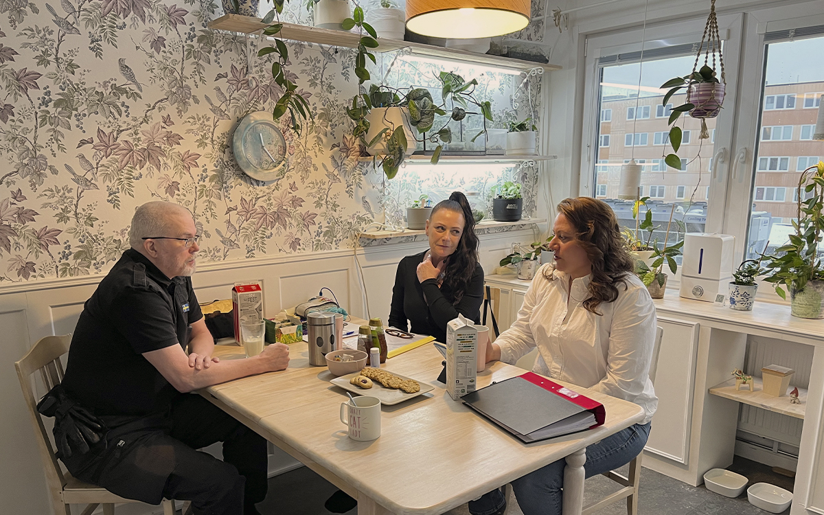 Tre hyresgäster sitter vid ett köksbord i en lägenhet i Fisksätra.