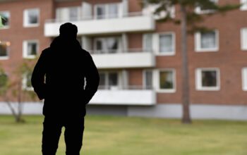 En skuggprofil framför ett flerbostadshus.