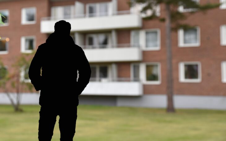 En skuggprofil framför ett flerbostadshus.