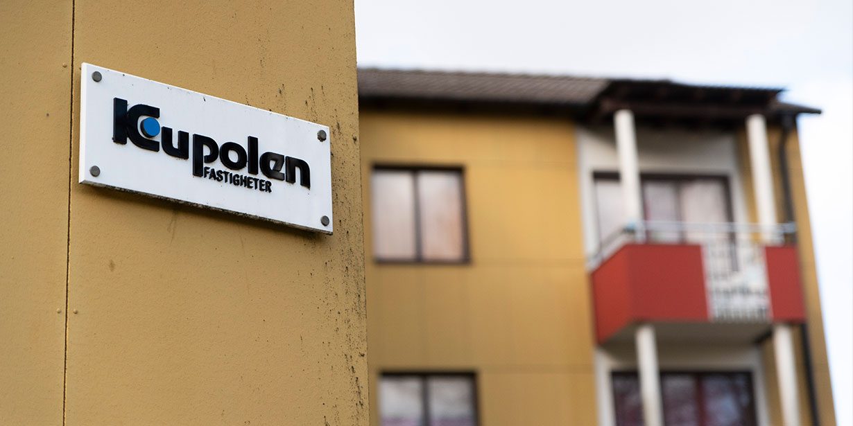Ett gult flervåningshus med en skylt med texten Kupolen fastigheter.