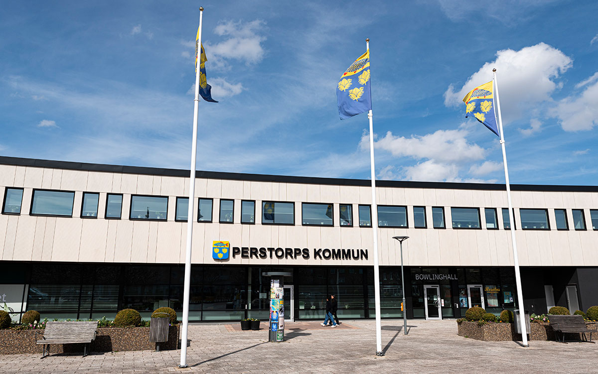 Ett hus med flaggstänger framför och texten Perstorps kommun.