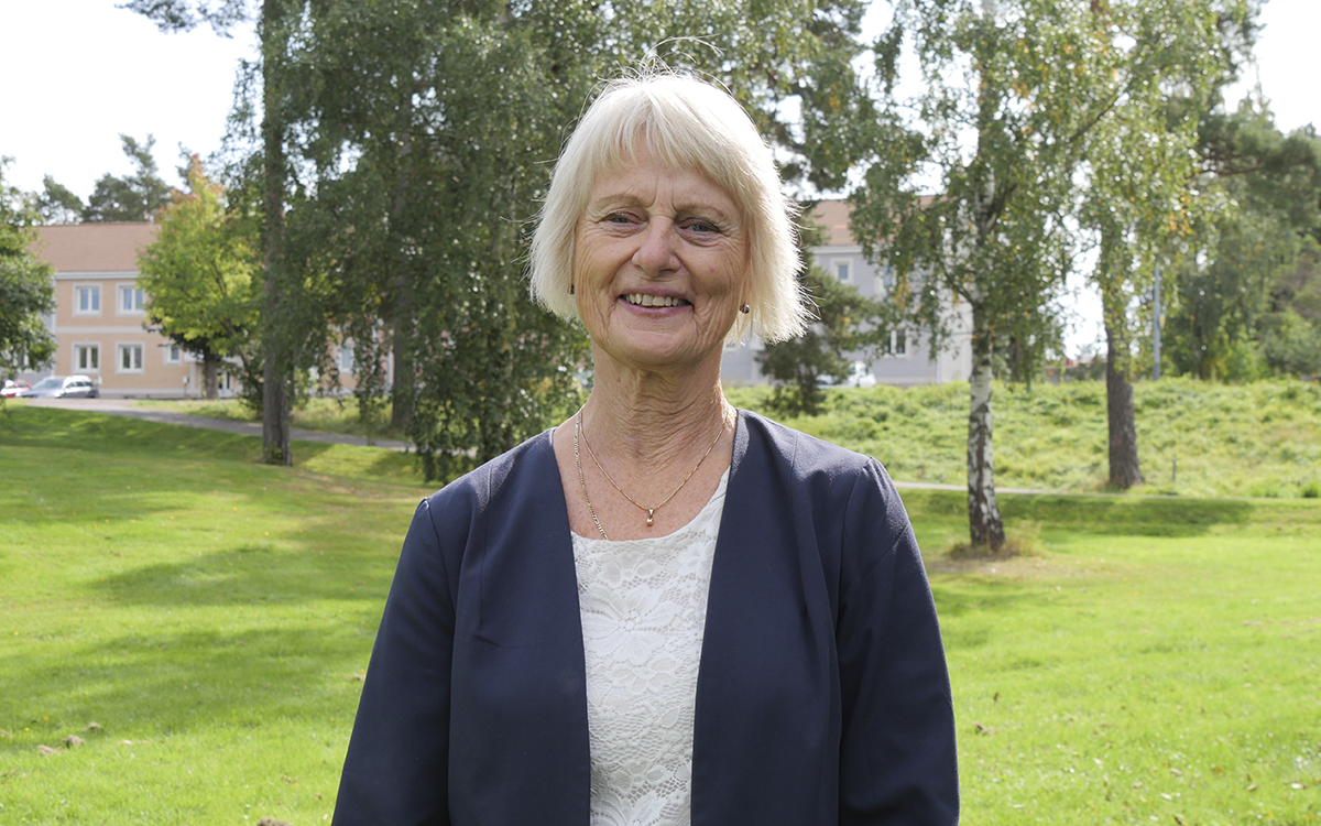 Halvkroppsporträtt på Solweig Gard i mörk kavaj och ljus topp, vit pagefrisyr med lugg. I Bakgrunden grönt gräs, träd och hus. Solweig Gard (S) i Hammarö kommun tycker att hyresgäster dubbelbeskattas av värdeöverföringar.