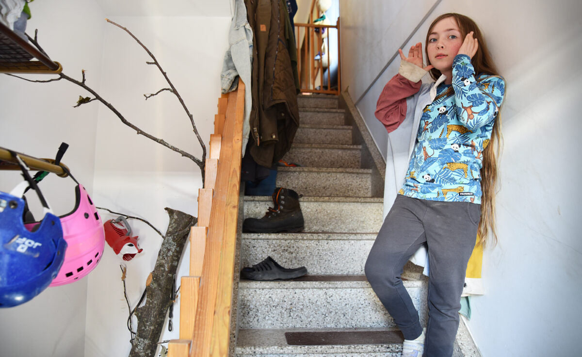 En tjej på trappan mot vilken en trädstam lutar sig.