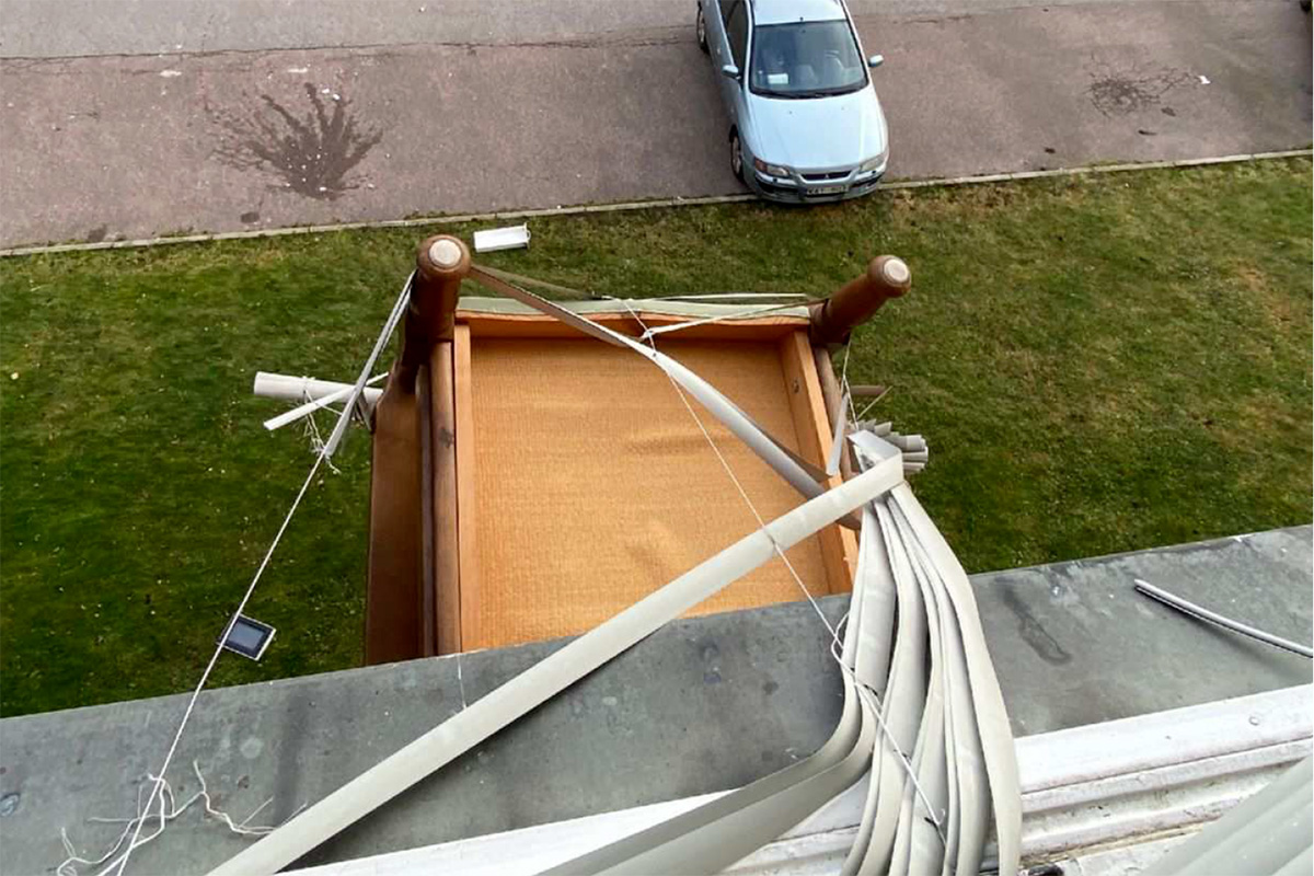 En stol hänger ut genom ett fönster.