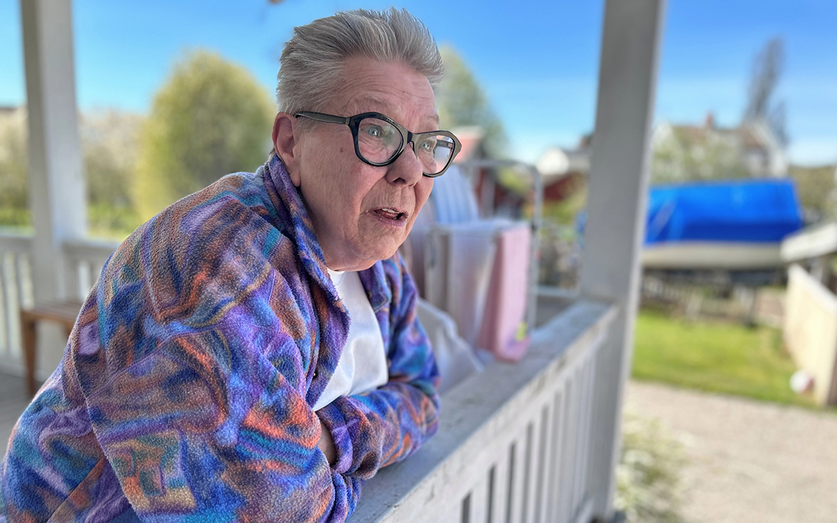 En kvinna som står på en veranda och lutar sig mot ett vitt räcke.