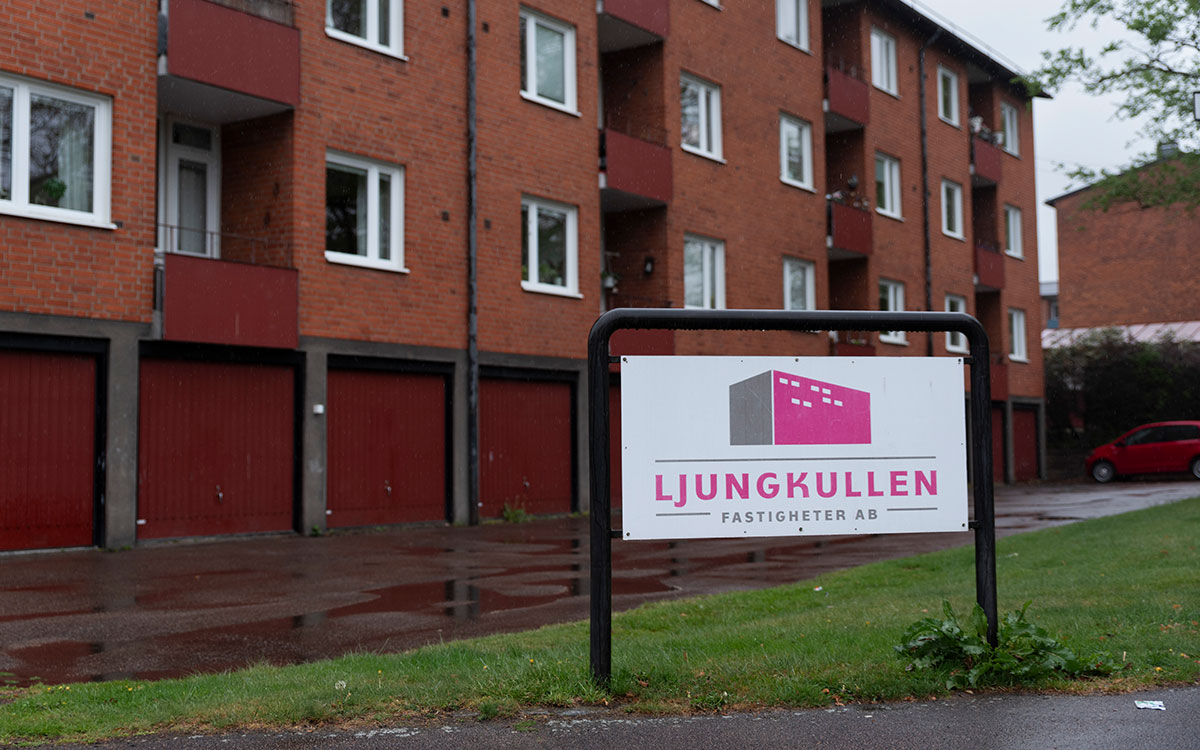 Flerbostadshus i tre våningar och rött tegel bakom en skylt med texten Ljungkullen Fastigheter AB.