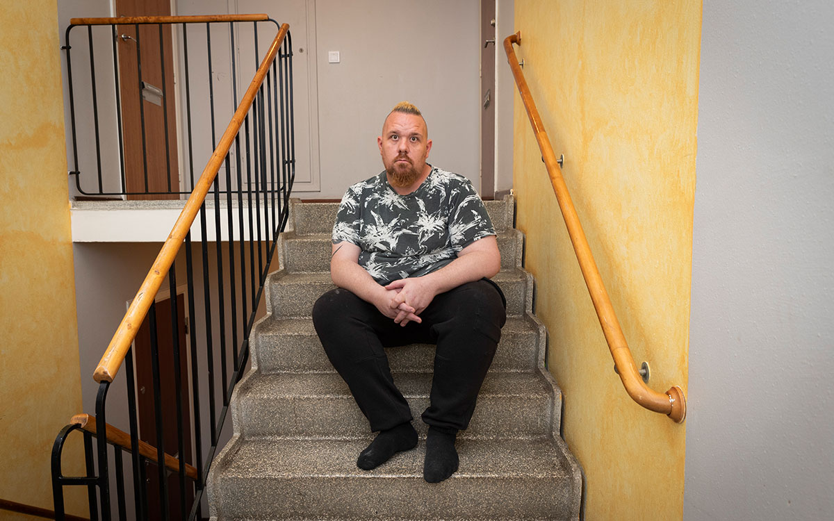 En man med mohawk och skägg sitter i trapphuset.