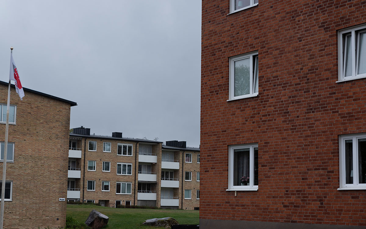 I förgrunden finns en flervåningsbyggnad i rött tegel och i bakgrunden en flervåningsbyggnad i gult tegel och en skylt med orden 