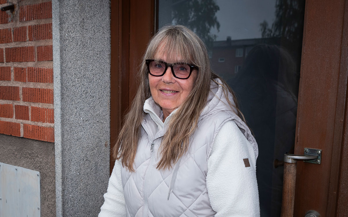 En äldre kvinna med glasögon, långt hår och en vit jacka.