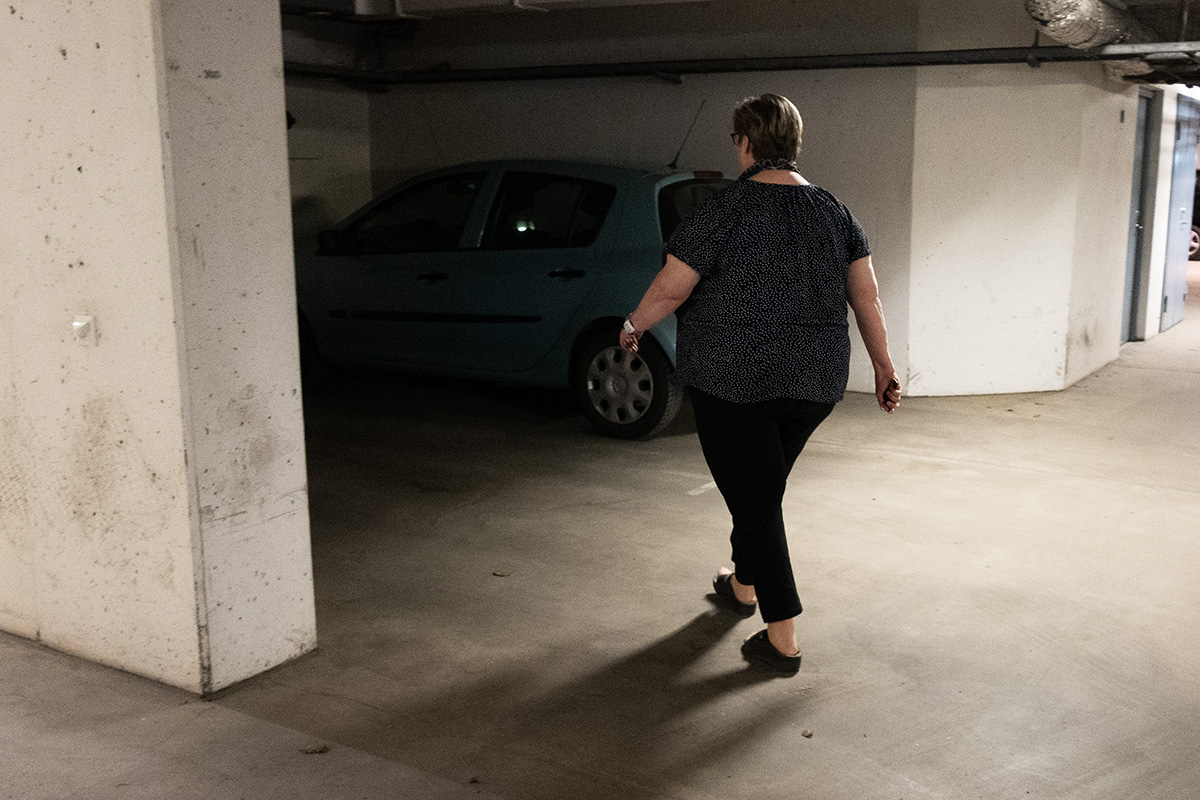 En kvinna som går mot en bil i ett mörkt garage.