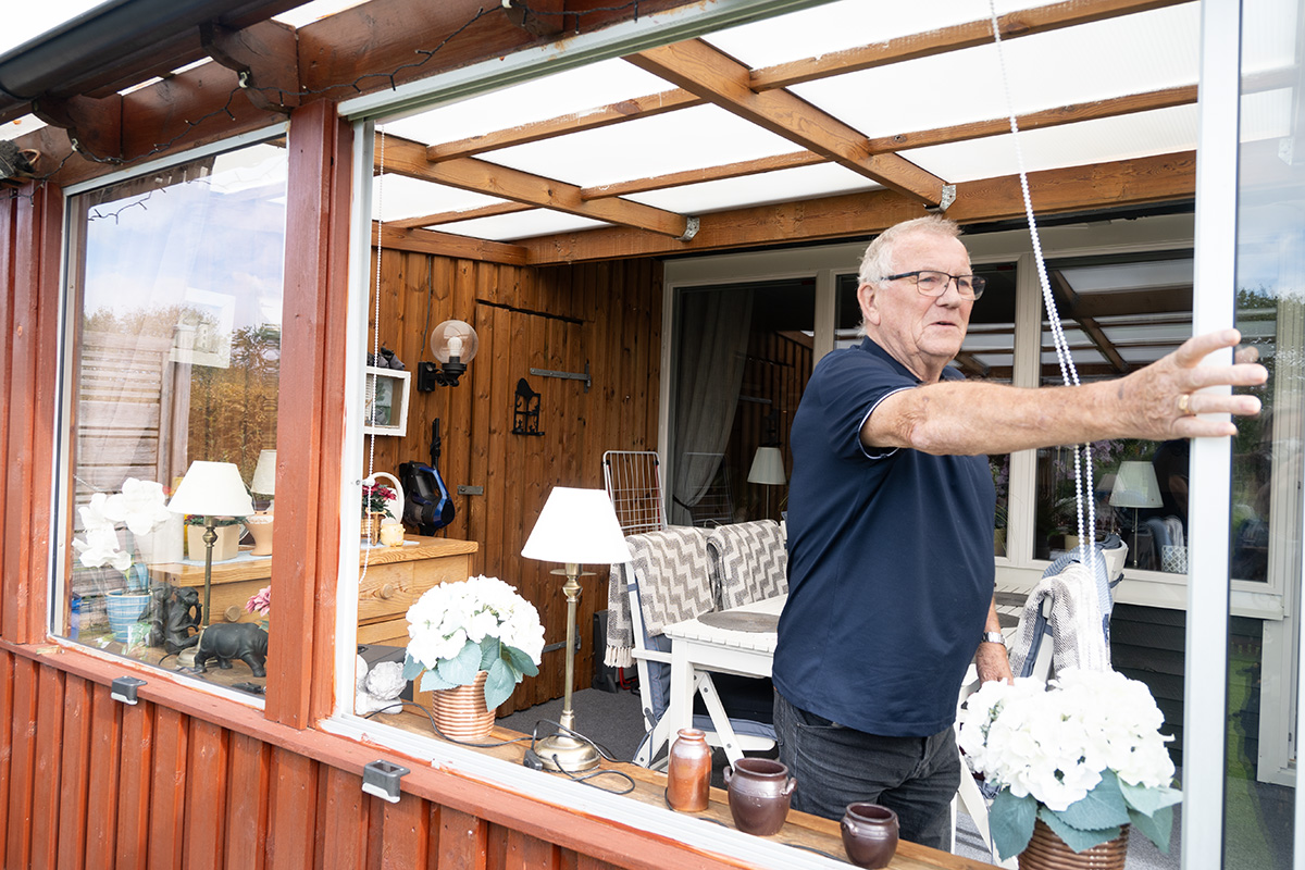 En man som skjuter undan ett fönster i ett uterum.