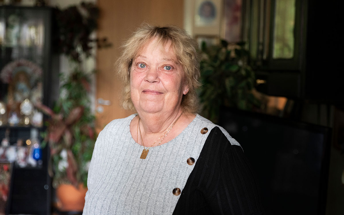 En äldre kvinna som står i ett vardagsrum.