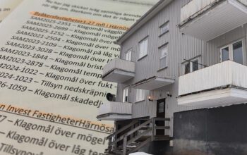 Ett gråmålat slitet trähus monterat med en bakgrund av papper med klagomålslista.